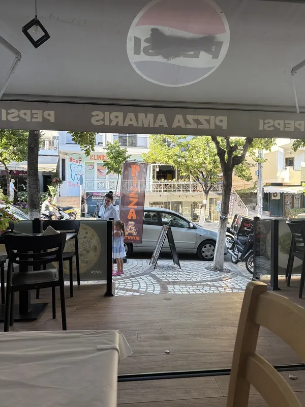 Looking out from the open front of Pizza AMARIS onto the street by day
