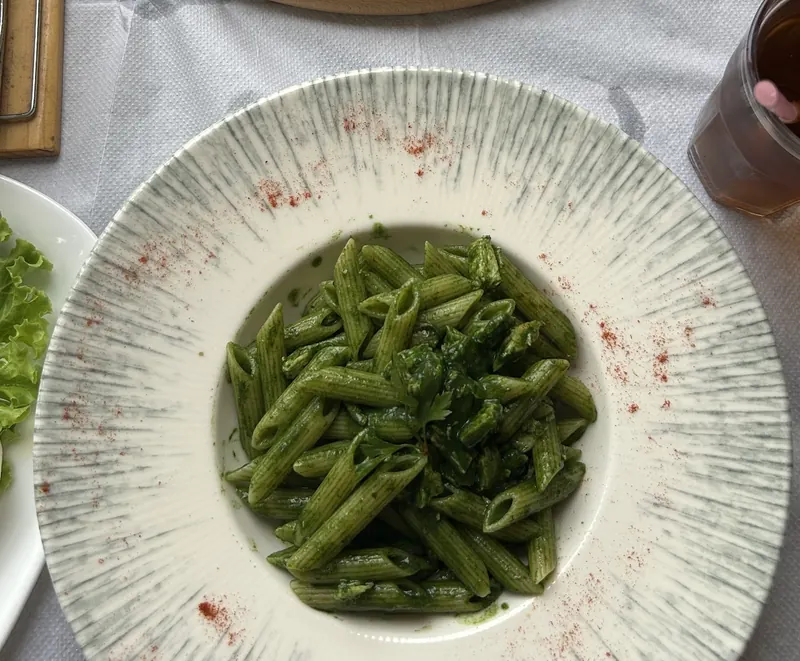Green penne in a wide white bowl
