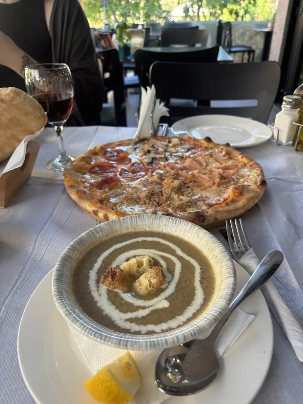 Cream soup, a pizza and a glass of red wine on the terrace